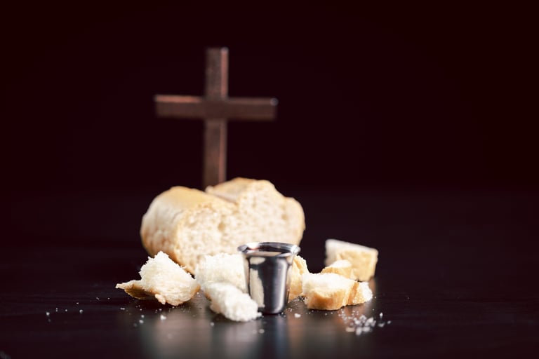 Communion bread, wine cup and cross on dark background